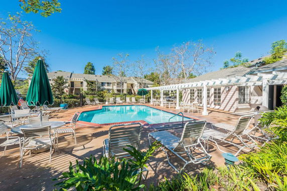 Outdoor swimming pool area with lounge chairs and sun umbrellas.