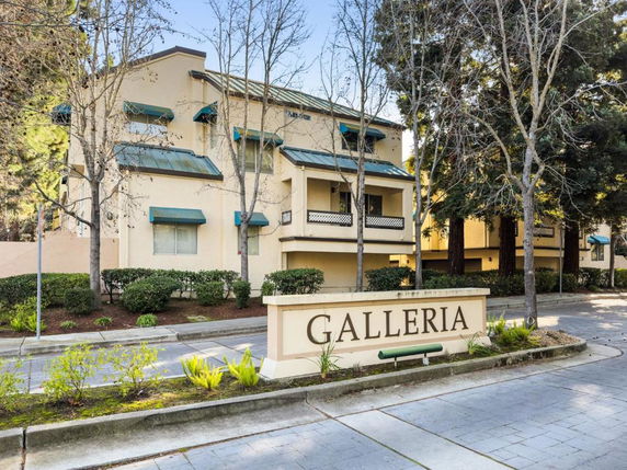 Front view of a multi-story building with green awnings and balconies.