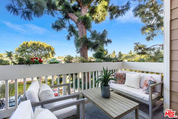 Balcony view with seating area overlooking trees.