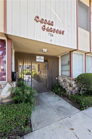 Entrance view of a building named Cedar Gardens with a gate and no trespassing sign.