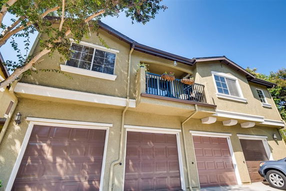 Front view of a two-story house with three garage doors and a small balcony.