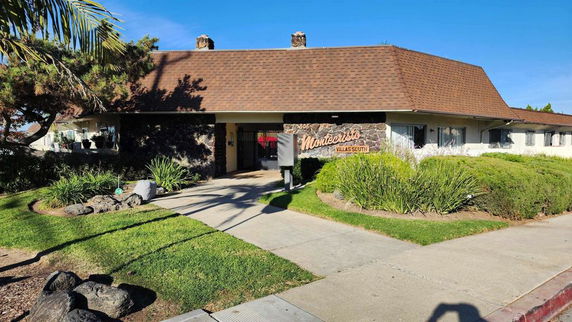 Front view of a single-story building with a sloped roof and entrance sign.