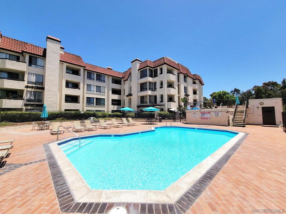 Outdoor swimming pool area with surrounding multi-story residential buildings.