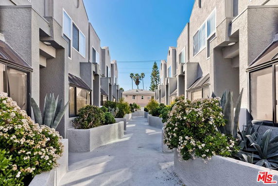 Front view of a modern residential building with multiple units and landscaped walkway.