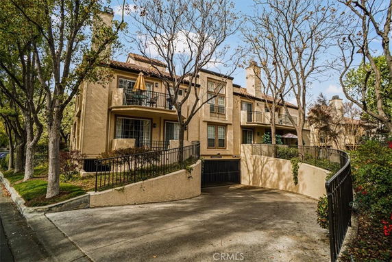 Front view of a multi-story building with balconies and a driveway.