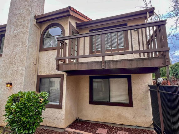 Front view of a two-story house with a small balcony and large windows.