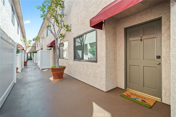 Exterior view of a building with entrance doors and red awnings along a walkway.