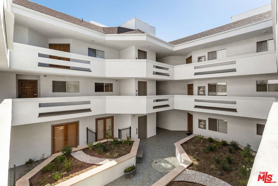 View of a multi-story building's interior courtyard with balconies and doors leading to individual units.