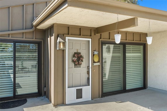 Front view of a house entrance with a door and two large windows.