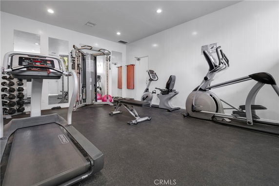 Indoor gym with exercise equipment including treadmills, stationary bikes, and weight machines.