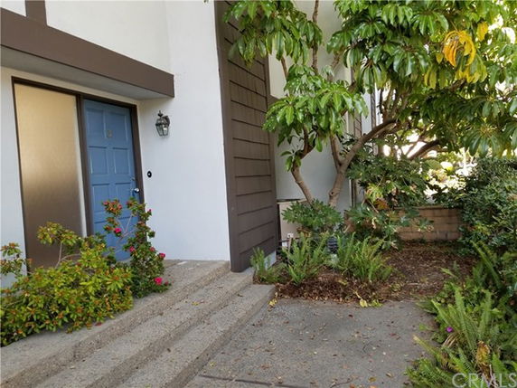 Front view of a house with a blue door and surrounding plants.