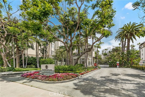 Front view of a mid-rise building surrounded by trees and landscaped gardens.