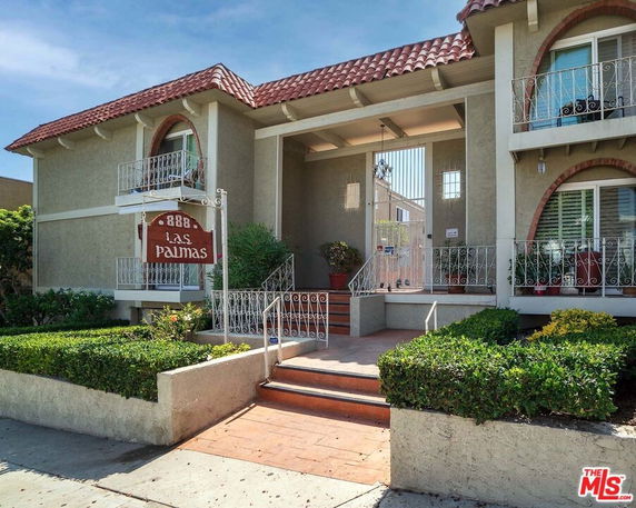 Front view of a two-story building with decorative balconies and a red tiled roof.