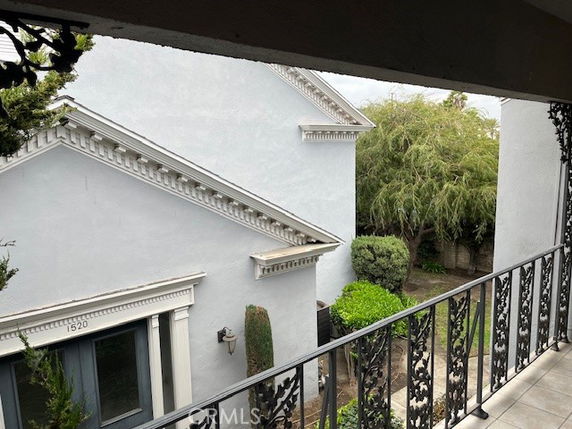 View from a balcony overlooking a house with white exterior and decorative railings.