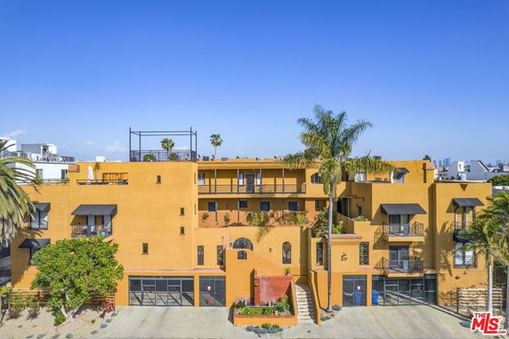Front view of a multi-story building with balconies and palm trees.