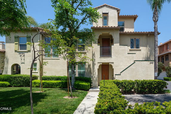 Front view of a multi-story house with beige stucco exterior and small balcony.