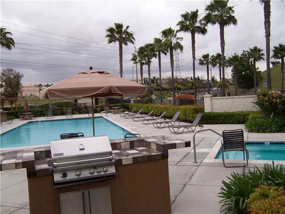 Outdoor swimming pool area with lounge chairs and a barbecue setup.