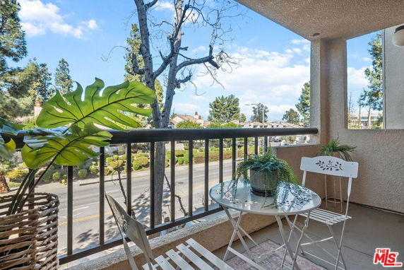 Balcony view overlooking a street with trees and houses.