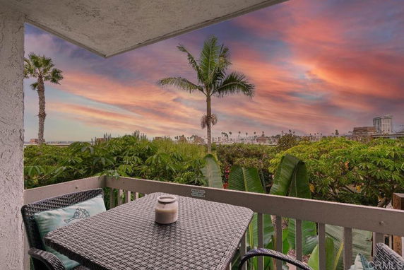 Outdoor patio with a table and chairs overlooking a lush green landscape and a colorful sky during sunset.