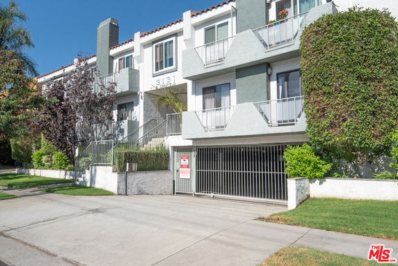 Front view of a multi-story building with balconies and gated entrance.