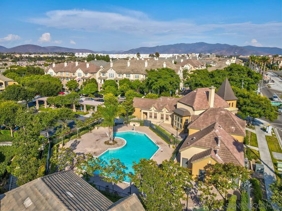 Aerial view of a residential complex with a central swimming pool surrounded by trees and buildings.