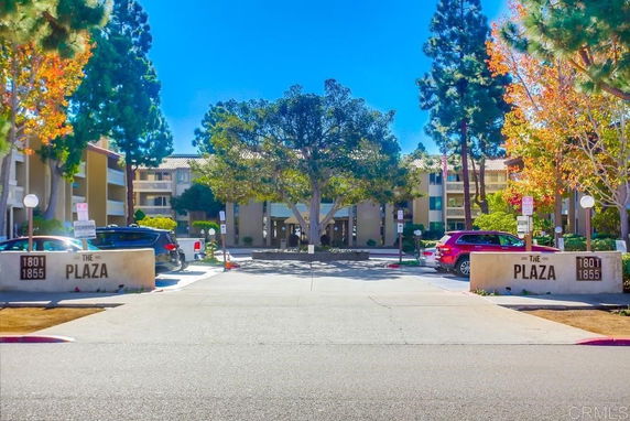 Front view of a multi-story building complex with parking area in front.