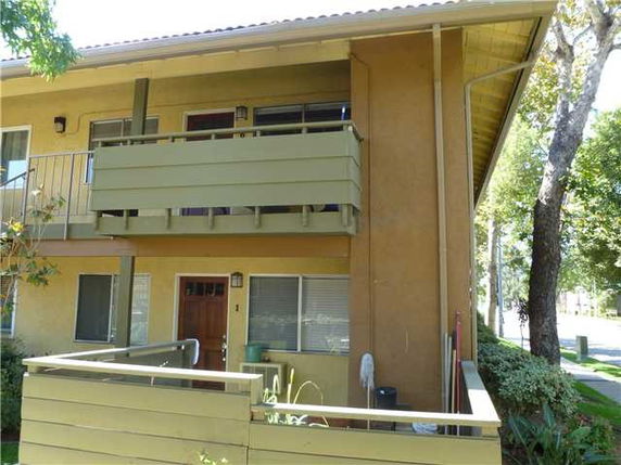Front view of a two-story building with a balcony and fenced entryway.