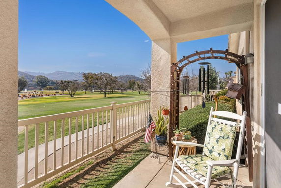 View from a porch overlooking a grassy area with trees and hills in the background.