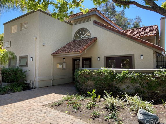 Front view of a two-story house with tiled roof and arched window.