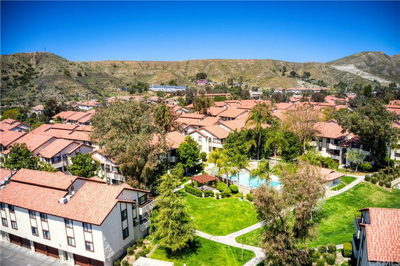 Aerial view of residential buildings with red tile roofs in a hilly area.
