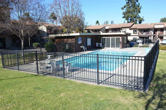 Swimming pool area enclosed by a fence in a residential complex.