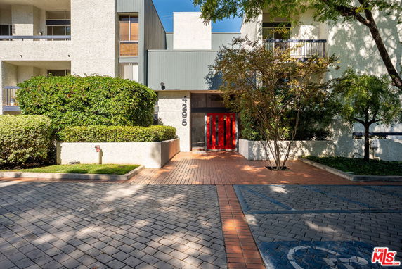 Front view of a building with a distinctive red door and brick pathway.