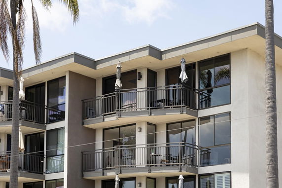 Front view of a multi-story apartment building with balconies and large windows.