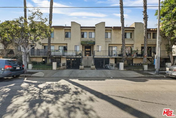 Front view of a multi-story residential building with balconies and entrance steps.