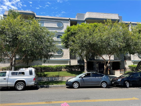 Front view of a multi-story building with circular windows and trees in front.