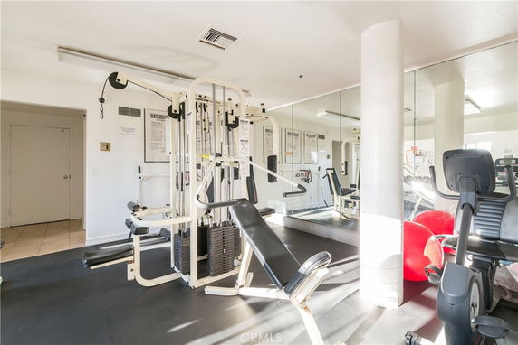 Indoor gym area with exercise equipment and mirrored walls.