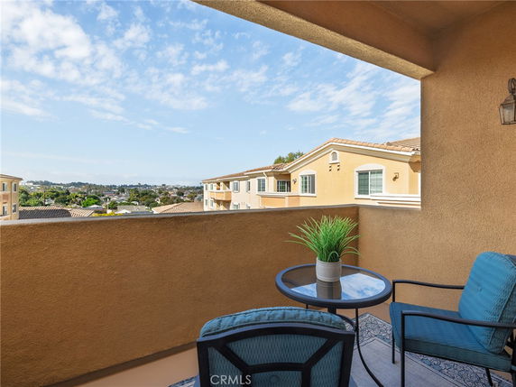 View from a balcony with outdoor seating and distant landscape.