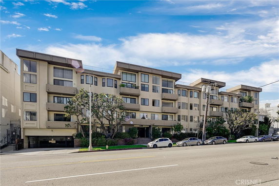 Front view of a multi-story apartment building with balconies and large windows.