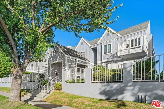 Front view of a multi-story residential building with balconies and a gated entrance.