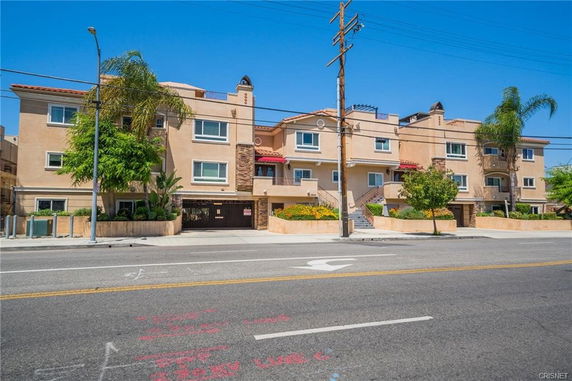 Front view of a multi-story residential building with a gated entrance.