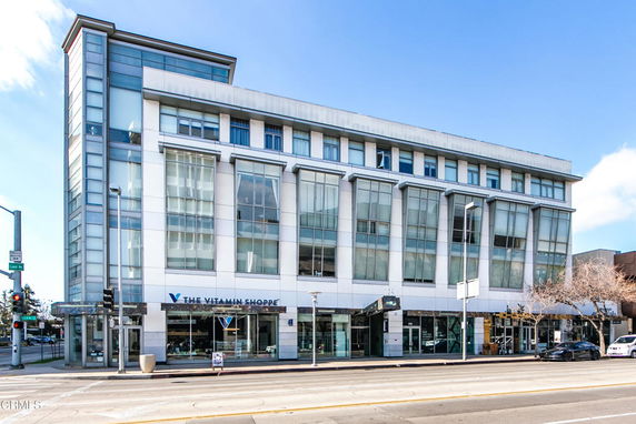 Front view of a multi-story commercial building with large windows and store signs.