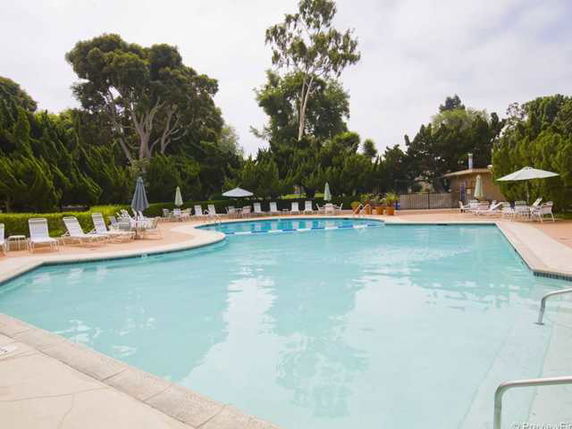 Outdoor swimming pool with surrounding lounge chairs and umbrellas.