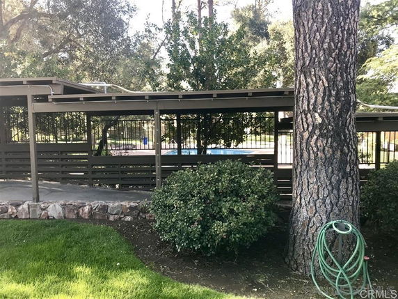 Outdoor swimming pool area surrounded by fencing and trees.