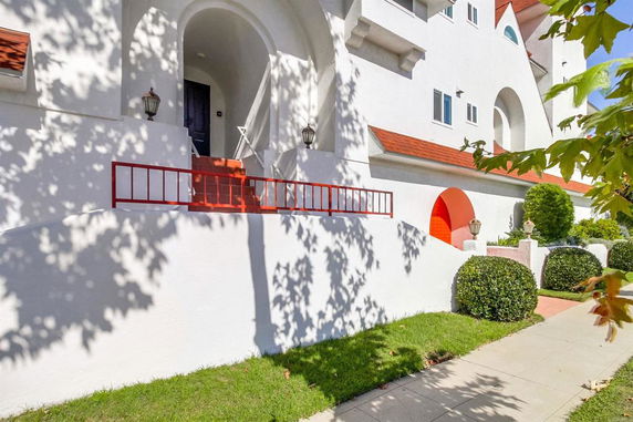 Front view of a multi-story building with red accents and arched doorways.