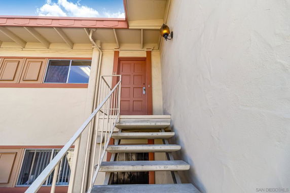Front view of a building with an exterior staircase leading to a door on the upper level.