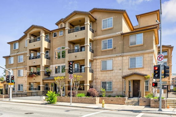 Front view of a multi-story apartment building with balconies and a central entrance.