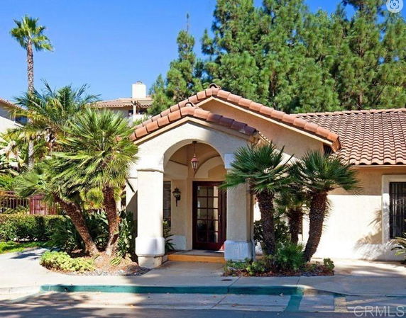 Front view of a house with an arched entryway and tiled roof.