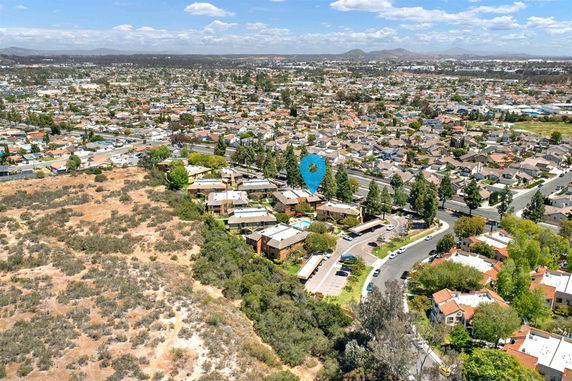 Aerial panoramic view of a residential area with numerous houses and surrounding landscape.