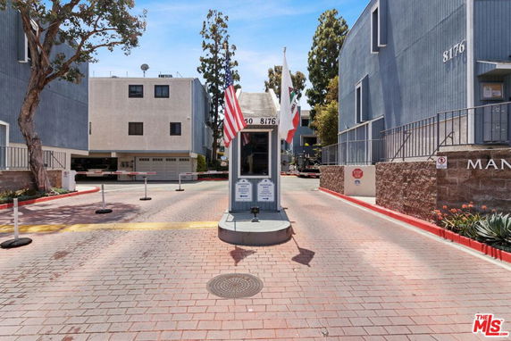 Entrance with guard booth surrounded by multi-story residential buildings.