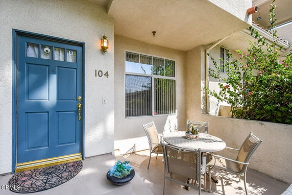Front view of a house with a blue door and porch seating area.